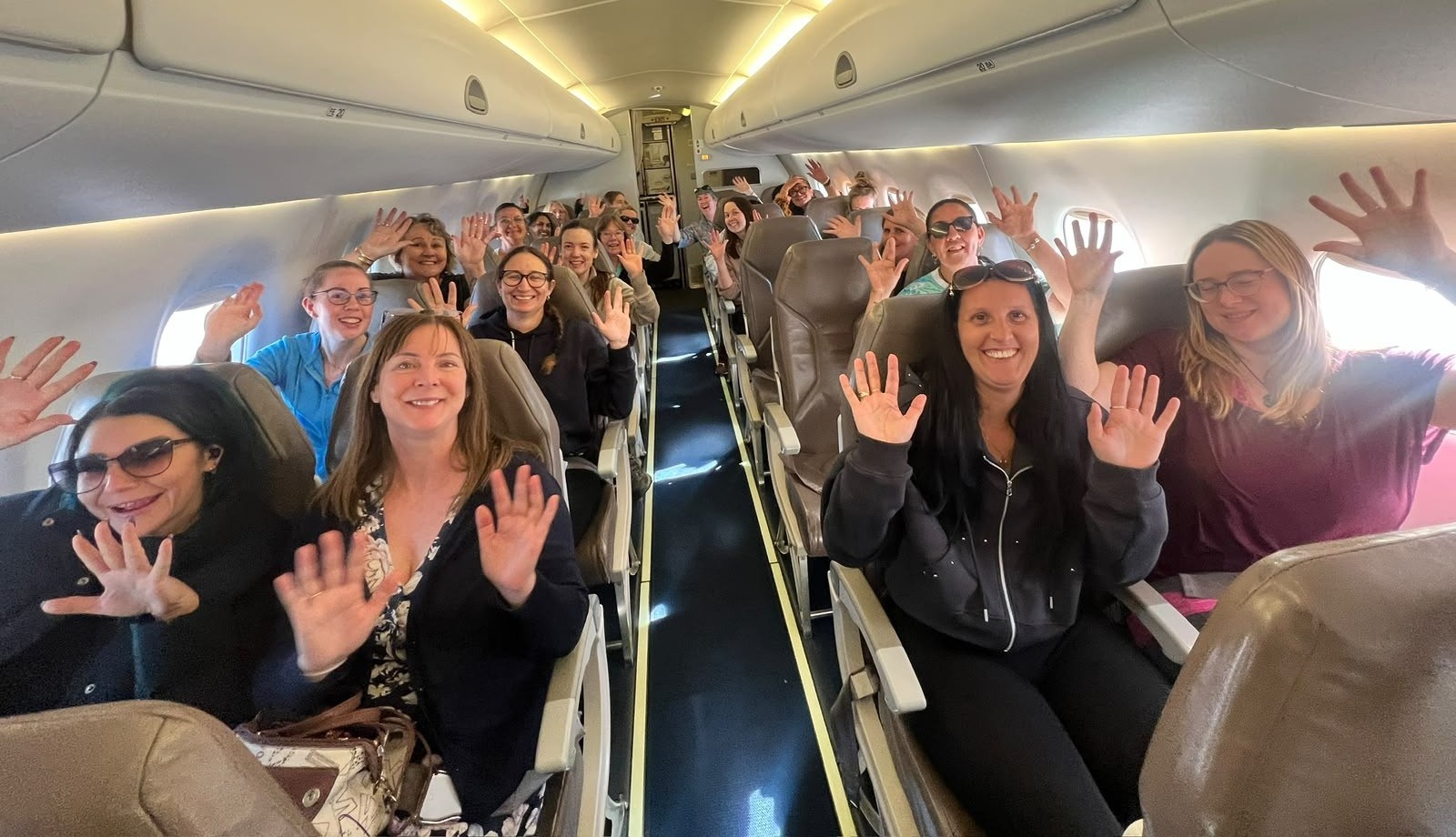 Ladies HQ women smiling and waving aboard the plane on their Red Centre adventure